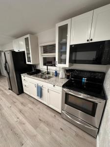 夏延2BR Gem: Modern Comfort & Style的厨房配有白色橱柜和不锈钢用具
