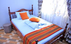 NjaraHeavenly Royalz Farm Fortportal的一张带橙色和蓝色枕头的床