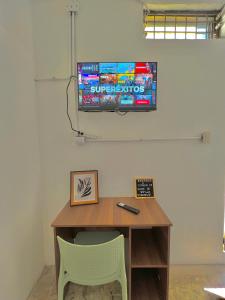 危地马拉Hotel Citadin zona 5的一张桌子、两把椅子和墙上的电视