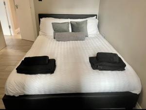布莱顿霍夫City Centre Seaview Apartment的一张白色的床,上面有两条黑色的毛巾
