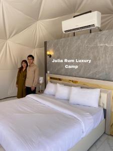 瓦迪拉姆Julia Rum Luxury Camp的站在大床旁边的男人和女人