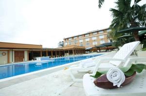 莱蒂西亚Hotel Anaconda的酒店旁的游泳池设有白色躺椅