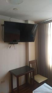 齐克拉约Hospedaje Concordia的一间房间,墙上设有一张桌子和一台电视机
