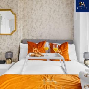 伯明翰2 Bed by Birmingham Airport的一张带橙色枕头的床和一个带两杯眼镜的托盘