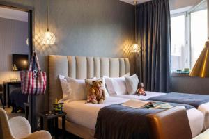圣雅克德拉朗德Best Western Plus Hôtel Isidore的两个泰迪熊坐在酒店房间的床边