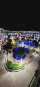 布兹尼盖COSTA BEACH Lux Family Apartment with Pools的一座楼前棕榈树的大型游泳池