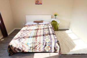 马卡姆壹家民宿的一间卧室配有一张带五颜六色被子的床