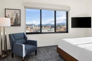博兹曼波兹曼元素酒店的一间卧室配有一张床、一把椅子和一个大窗户