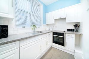 伦敦Brewer Street Central Apartments的白色的厨房配有白色橱柜和水槽