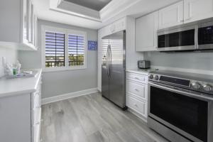 萨尼贝尔Loggerhead 314 condo的厨房配有白色橱柜和不锈钢用具