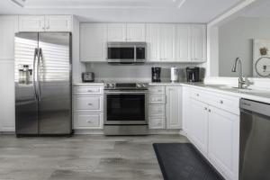 萨尼贝尔Loggerhead 314 condo的厨房配有白色橱柜和不锈钢冰箱