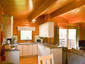 LegbourneRed Kite Lodge的厨房配有白色橱柜和木制天花板
