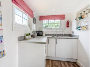 考布里奇Gwyneths Haven - Uk46404的厨房配有白色橱柜和水槽