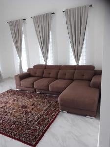 MacangHomestay Rumi的客厅里一张棕色的沙发,铺着地毯