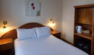 肯图巴肯图巴大都会宾馆的一间卧室配有一张带白色床单和两盏灯的床。