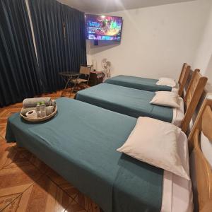利马Lima Airport Hostel with FREE AIRPORT PICK UP的一间设有三张床的客房,墙上设有一台电视。