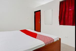 坎普尔OYO Flagship City Light Hotel的一间卧室配有一张带红色窗帘的床