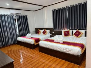 万荣VangVieng Charming Boutique Hotel的配有窗帘的酒店客房内的两张床