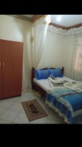 VoiTHE DESERT ROSE HOTEL VOI的一间卧室配有一张带蓝色床单的床和一扇窗户。