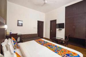 新德里FabHotel City Chalet Saket的一间卧室配有一张床、一张书桌和一台电视。