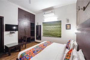 新德里FabHotel City Chalet Saket的一间卧室配有一张床、一张书桌和一台电视