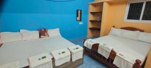蒂鲁瓦纳马莱Pushpa Mahal A/C & Pushpa Residency的蓝色墙壁客房的两张床