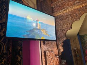 WinglesChambre & Spa "La Casa Blue"的墙上的平面电视,上面有灯塔的照片