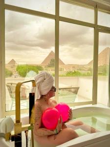开罗Tree Lounge Pyramids View INN , Sphinx Giza的坐在浴缸里拿着一个粉红色气球的女人