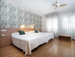 沙比纳尼哥我家酒店的卧室配有一张白色大床和吊扇。