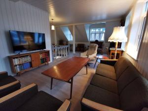 努尔菲尤尔埃德Sjarmerande hus i Eidsgata的带沙发、桌子和电视的客厅