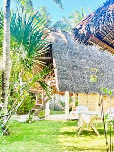 邦劳Boholala hostel的庭院中带茅草屋顶和长凳的房子