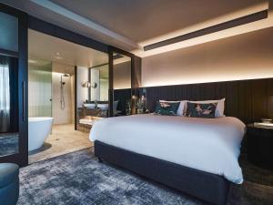 墨尔本墨尔本公园铂尔曼酒店&度假村的一间卧室设有一张大床和一个浴缸