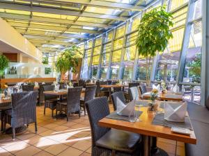 哈尔伯格摩斯瑞享姆赫尔机场酒店的餐厅设有木桌、椅子和窗户。
