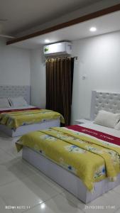 达卡Hotel living international ltd.的配有两张黄色和红色床单的床铺