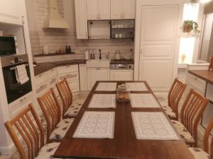 布达佩斯Kúria apartman with private jacuzzi and pool的一间带木桌和椅子的厨房和一间带白色橱柜的厨房