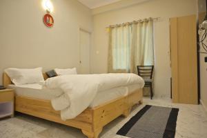 瓦拉纳西Stay Inn Kaashvi (A unit of Admire India Tourism Pvt. Ltd.)的一间卧室配有一张大木床和白色床单