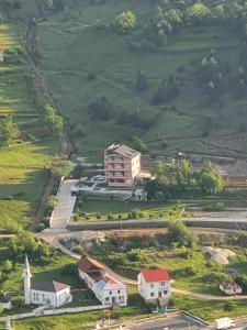 PeshkopiLURA Hotel的享有山上房屋的空中景致,设有教堂