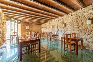瓦德诺比斯HOTEL EL CASTELL的一间设有木桌和椅子的餐厅以及石墙