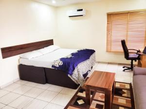 AsoCentral District Apartment (Abuja)的卧室配有1张床、1张桌子和1把椅子