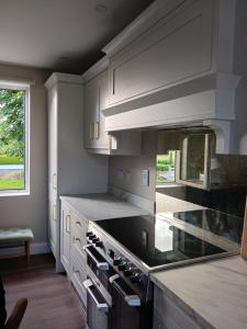 Wood View Cottage的厨房配有白色橱柜和炉灶烤箱。