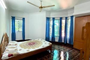巴纳内拉斯Kumar Para Deluxe Villa的一间卧室配有一张带蓝色窗帘的床和风扇