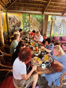 阿鲁沙Safari villa的一群坐在餐桌上吃食物的人