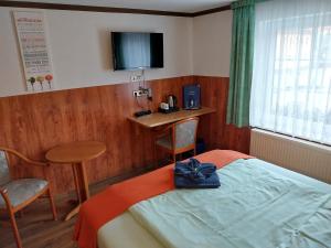 SohlandLandhotel Waldschlößchen的一间卧室配有一张床、一张桌子和一台电视
