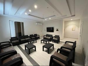 SulţānahMadinah Valley Residency Room 1的一间设有黑色椅子和平面电视的等候室