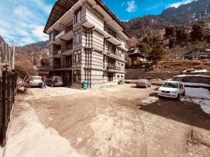 马拉里Hotel Kanchani - A Majestic Mountain Retreat的一座大型建筑,前面有汽车停放