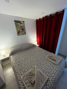 芒通Petit coin de paradis的一间卧室配有一张带红色窗帘的床