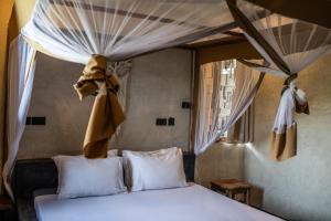 江比阿Baobab Bungalows的一间卧室配有床,床的上方配有窗帘