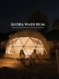 瓦迪拉姆Alora Wadi Rum Luxury的男人和女人在晚上坐在帐篷里