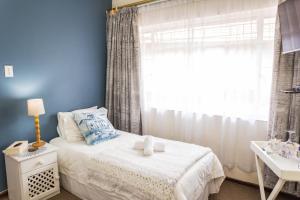 逊邱伦Rozendal Guest House的卧室配有白色的床和窗户。