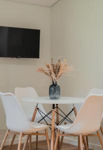 比索达雷加Primeiro Quartel Apartments - 4的一张桌子,上面有两把白色的椅子和花瓶